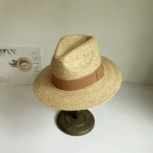 Nahaufnahme des handgeflochtenen Bast-Sonnenhutes mit braunem Band für Sommeroutfits.