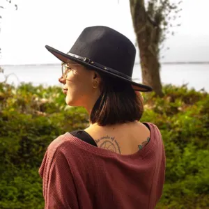 Detailansicht eines eleganten schwarzen Fedora-Hutes mit Gürtelschnalle im Außenbereich.