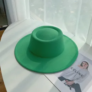 Detailopname van de groene wollen vilten hoed met brede rand en platte bovenkant.