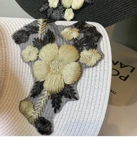 Detailansicht der schwarz-goldenen Blumenstickerei am sommerlichen Strohsonnenhut.