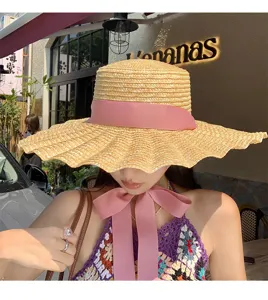 Dettaglio del cappello di paglia con trama intrecciata ed elegante nastro rosa.