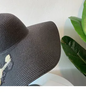 Detailansicht des schwarzen Strohsonnenhutes mit Blumenstickerei, elegantes Sommermode-Accessoire.