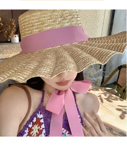 Primo piano del cappello di paglia a tesa larga con nastro rosa, stile vacanza estiva.