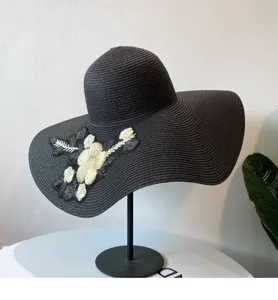 Detaillierte Ansicht des schwarzen Strohhutes mit Blumenstickerei und breiter Krempe für den Sommer.