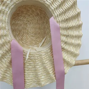 Vista dettagliata del cappello di paglia a tesa larga con nastro rosa per la spiaggia estiva.