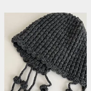 Nahaufnahme Detail der handgestrickten Damen Beanie Mütze mit Quasten und warmen Ohrenklappen.