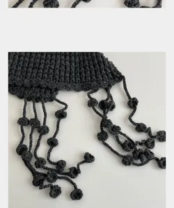 Handgemachte dunkelgraue Strickmütze Detail mit Quasten und Bommeln, warmer Winterartikel.