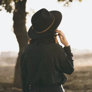 Detailed view of a stylish black fedora hat with brown leather belt decoration.