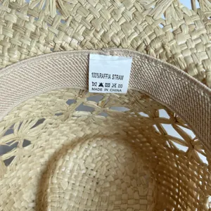 Close-up detail view of the 100% raffia straw hat interior label and natural woven texture.