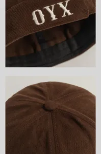Détail d'un bonnet docker marron en velours côtelé avec broderie blanche OYX sur le bord.