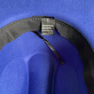 Close-up detail of blue fedora hat interior showing quality fabric and washing label.