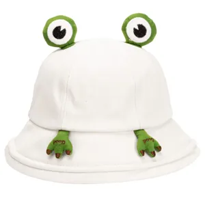 Close-up detail of white bucket hat with cute 3D cartoon frog eyes and embroidered hands.