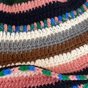 Close-up detail of retro color-block handmade knit bucket hat colorful woolen texture.