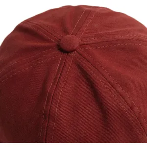 Detailansicht der oberen Nähte und des Knopfdesigns einer stilvollen roten Docker Cap.