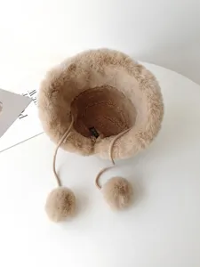 Detail view of winter plush bucket hat with drawstrings and fluffy pom poms, warm winter hat.