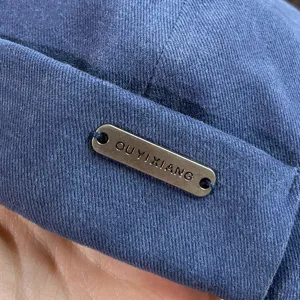 Λεπτομέρεια μπλε καπέλου docker από βαμβάκι με διακόσμηση μεταλλικής ετικέτας.