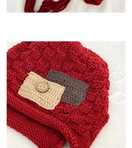 Detail shot of red knitted wool hat with decorative mini pockets and wooden button.