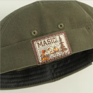Close-up detail of the retro dark green docker cap featuring an embroidered mountain badge.