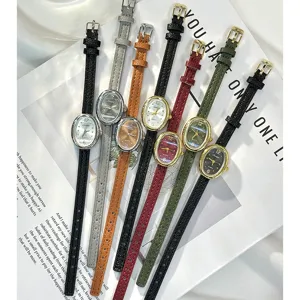 Detail view of vintage small oval women quartz watch with thin leather strap, elegant style.