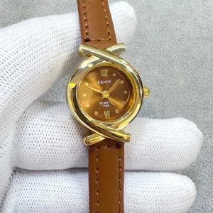 Close-up detail of women quartz watch, brown leather strap, gold cross case design.