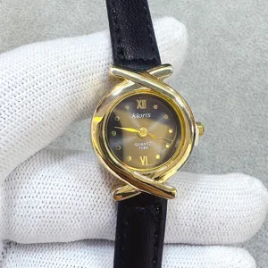 Detail view of kloris women quartz watch, elegant black leather strap and unique gold cross case.