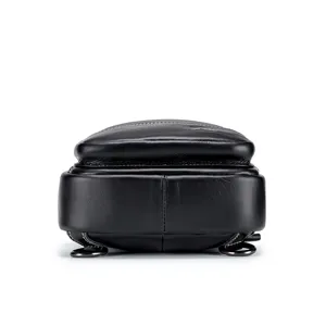Bottom detail view of black genuine leather chest bag, showing fine stitching and metal rings.