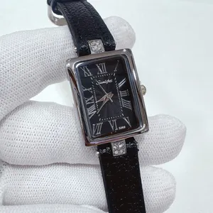 Primer plano de un reloj de mujer vintage rectangular con esfera negra y correa de cuero.