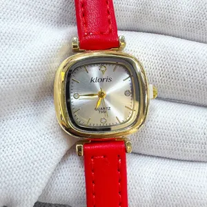 Detailed closeup view of red leather strap with gold square case quartz watch dial