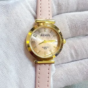 Close-up detail of women quartz watch with pink leather strap, gold round case and numeric dial.