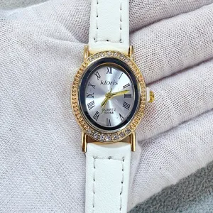 Close-up of women's quartz watch with white leather strap and rhinestone oval bezel.
