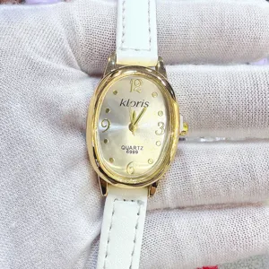 Detailaufnahme der goldenen ovalen Quarzuhr mit weißem Lederarmband und klaren Ziffernblatt.