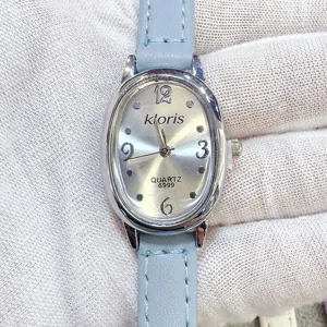 Nahaufnahme der kloris Damen Quarzuhr, silbernes ovales Zifferblatt mit blauem Lederarmband.