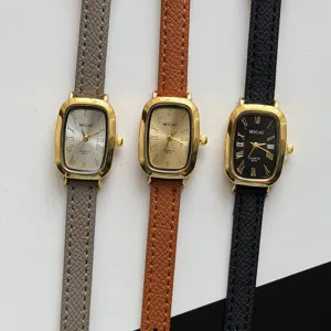 Détail de la petite montre rectangulaire vintage avec bracelet en cuir et boîtier doré.