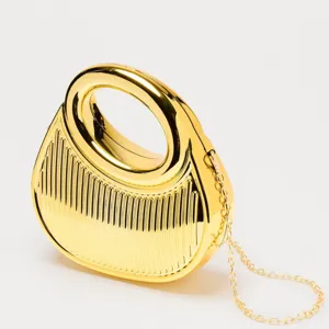 Gold acrylic evening bag detail featuring a chic ring handle and shiny metal chain.