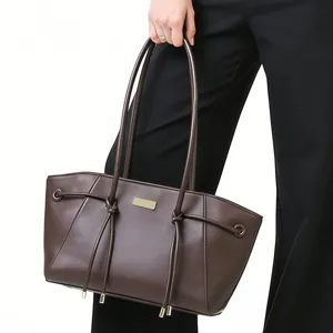 Detailed view of dark brown trapezoid tote bag with long straps and metal plate detail.