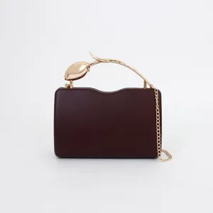 Detail shot of the dark red evening clutch with gold tulip metal handle and chic chain strap.