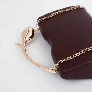 Detailed view of dark brown retro clutch bag with golden tulip handle and luxury chain.