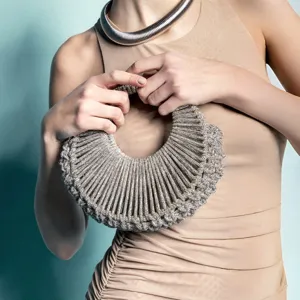 Gros-plan d'un sac de soirée hobo tissé en strass étincelant tenu par un mannequin élégant.