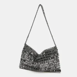 Détail de sac bandoulière en perles métalliques, élégant accessoire pour soirée chic.
