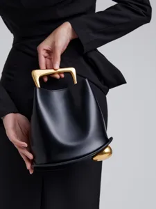 Elegant black leather bucket bag with distinctive sculptural gold metal top handle for women