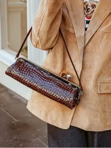 Detailed view of brown crocodile pattern baguette shoulder bag with metallic frame and clasp closure.