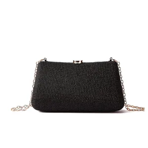 Magnifique détail de pochette de soirée tissée noire avec texture et chaîne dorée.