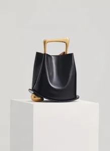 Stylish black leather bucket bag with unique gold handle and sphere accent for women fashion.