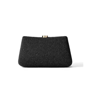 Vue détaillée d'une pochette noire tissée avec fermoir métallique doré pour soirée chic.