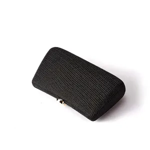 Gros plan détail du sac pochette de soirée tissé noir avec fermoir en métal, accessoire élégant.