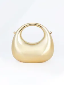 Détail de sac de soirée croissant en métal doré brillant avec poignée ronde élégante.