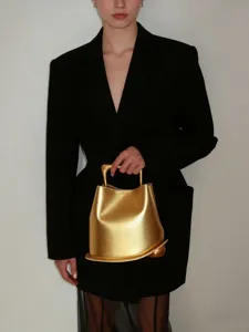 Stylish metallic gold bucket bag with unique handle and sculptural design for women.