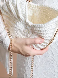 Détail de sac de plage en crochet blanc fait main, texture de fil complexe et chaîne dorée.