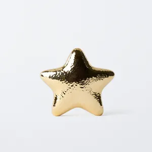 Golden metallic star evening bag detail, glossy textured zinc alloy clutch design.