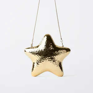 Close-up detail of the metallic gold star evening bag, showing the shiny surface.